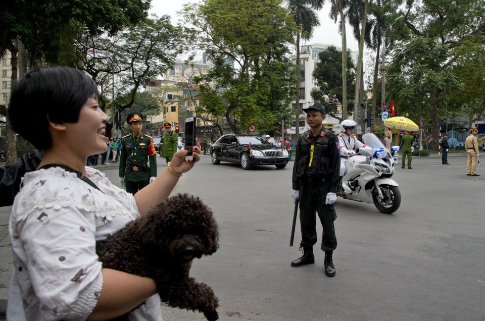 A woman with her pet dog watch as motorcade of North Korean leader Kim Jong Un is driven off Melia hotel in Hanoi, Vietnam, Saturday, March 2, 2019. (AP Photo/Gemunu Amarasinghe)