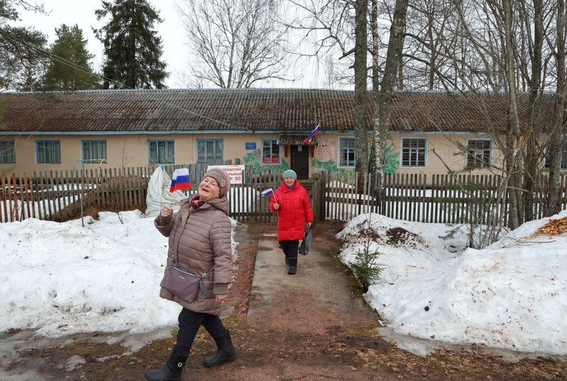 Varias mujeres portan banderas rusas a la salida de un colegio electoral durante las elecciones presidenciales en el pueblo de Pasha, en la región de Leningrado