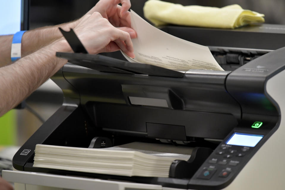 Cobb County Election officials run ballots through a machine, Tuesday, Nov. 24, 2020, in Marietta, Ga. County election workers across Georgia have begun an official machine recount of the roughly 5 million votes cast in the presidential race in the state. The recount was requested by President Donald Trump after certified results showed him losing the state to Democrat Joe Biden by 12,670 votes, or 0.25% (AP Photo/Mike Stewart)