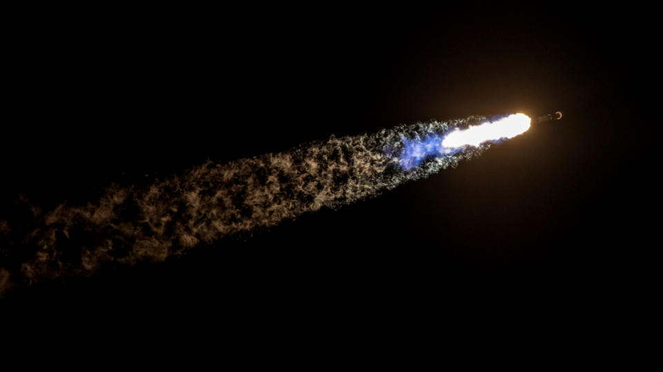 close-up look at the orange fire from a rocket's first stage as it climbs into a night sky.