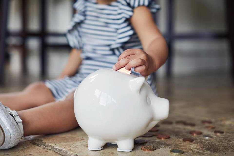 Little toddler girl saving money in her piggy bank