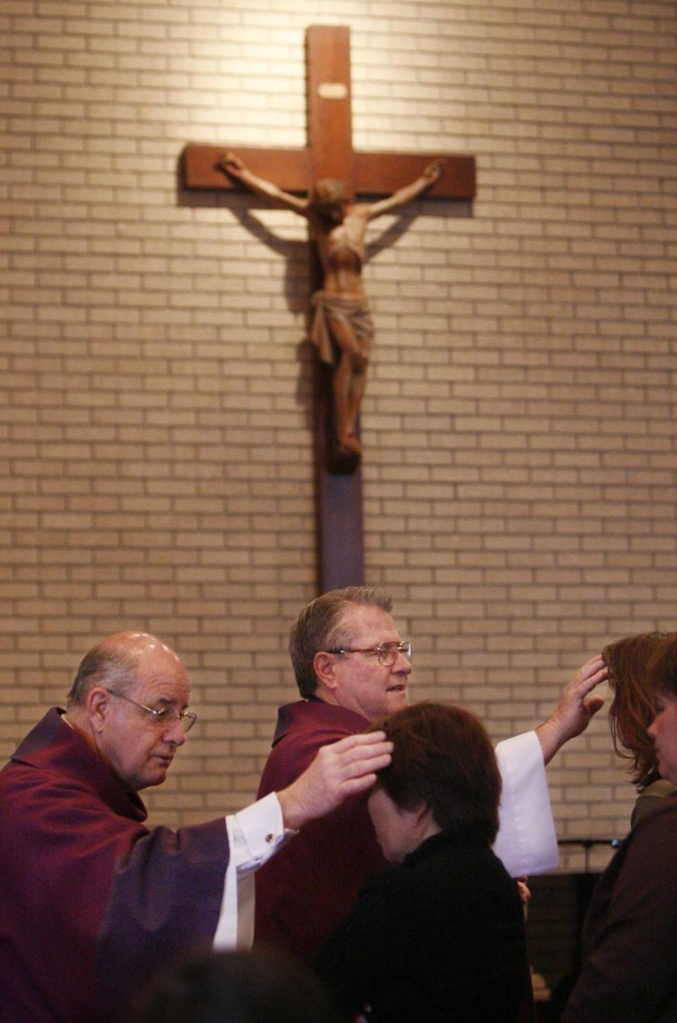 The Rev. George Kitchin (center) places ashes on parishoners at St. James Catholic Church in Gulfport during a 2007 Ash Wednesday service.