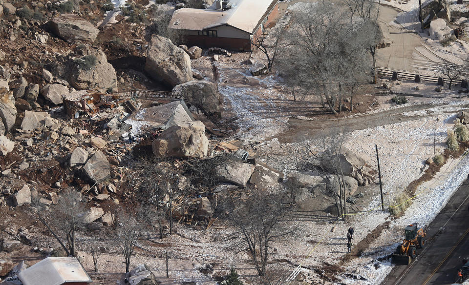 FILE - In this Dec. 13, 2013, file photo,officials survey the boulders from a rock slide that crushed a home and killed two people, in Rockville, Utah. Geologists are warning of the possibility of more rock slides in Utah like one in December that killed a middle-aged couple, flattening their cliff-side home near Zion National Park. The Utah Geological Society released its report Thursday, April 3, 2014, saying a massive sandstone slab near the one dislodged by rain and snow in December now threatens to crash and shatter onto the slope below. Officials say boulders could then crush a string of homes in Rockville, about 250 miles south of Salt Lake City. (AP Photo/The Deseret News, Tom Smart, File) SALT LAKE TRIBUNE OUT; MAGS OUT