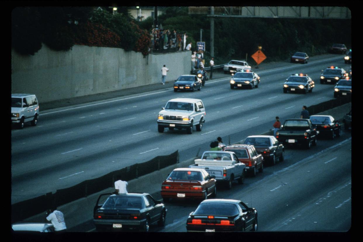LOS ANGELES: Automovilistas se detienen y saludan mientras las patrullas persiguen una camioneta Ford Bronco (blanca al centro) manejada por Al Cowlings, llevando al fugitivo y sospechosos de homicidio OJ Simpson, en una persecución a baja velocidad el 17 de junio de 1994 en la carretera 405 en Los Ángeles, California. El amigo de Simpson, Cowlings, posteriormente condujo hacia la casa de Simpson en Brentwood, donde se entregó a las autoridades. (Foto de Jean-Marc Giboux/Liaison)