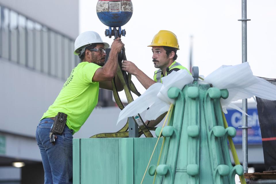 Rodrigo Cruz of JMD Contractors, left, and Dusty Conley of Prop Art Studio prepares a spires to be lifted into its place on the Mariners' Church in Detroit on Saturday, July 22, 2023.