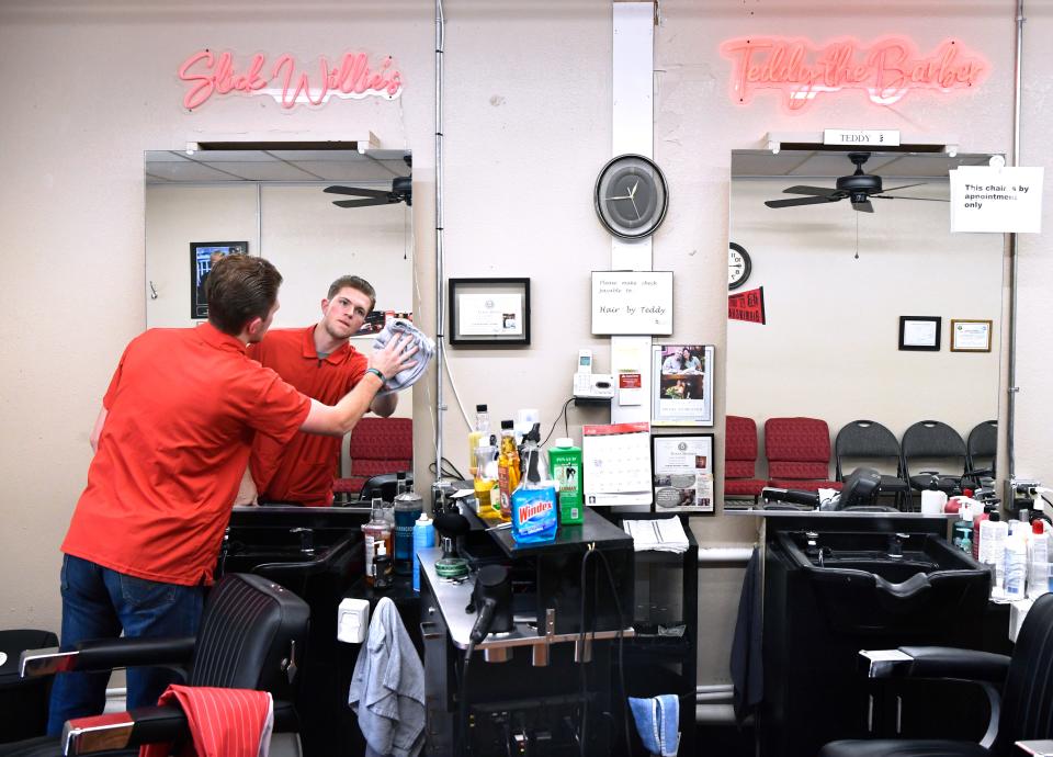 Will Cochran wipes the mirror for his station at River Oaks Barber Shop on Thursday. Cochran is co-owner with Teddy “The Barber” Gifford. The two barbers are 63 years different in age.
