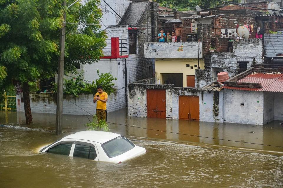 <div class="paragraphs"><p>Lucknow: A man stands near a partially submerged vehicle due to waterlogging following heavy rains on 16 September.</p></div>