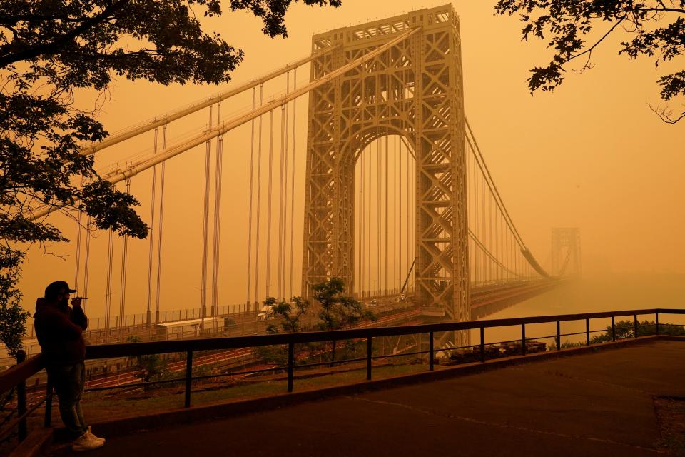 A man talks on his phone as he looks through the haze at the George Washington Bridge in Fort Lee, N.J., Wednesday, June 7, 2023. Intense Canadian wildfires blanketed the northeastern U.S. in a dystopian haze, turning the air acrid, the sky yellowish gray and prompting warnings for vulnerable populations to stay inside.