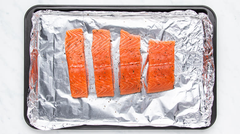 Seasoned salmon fillets on baking sheet