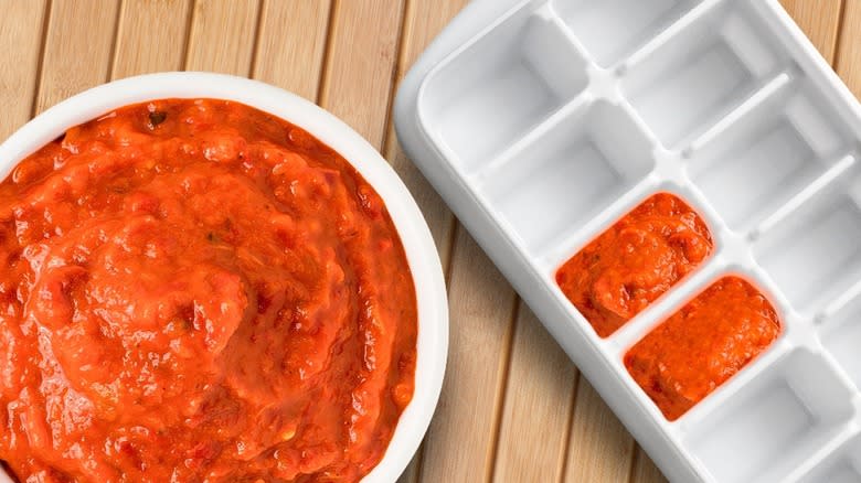 Top-down view of pasta sauce in a dish and an ice tray