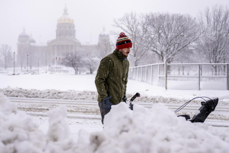 The Iowa State Capitol Building is visible as Spud Glaser of Carlisle, Iowa, plows the sidewalk in downtown Des Moines, Iowa, Tuesday, Jan. 9, 2024, as a winter snow storm hits the state. (AP Photo/Andrew Harnik)