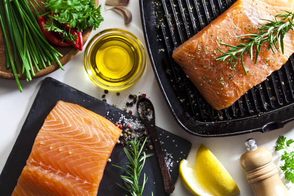 Top view of two raw salmon steaks ready for cooking. Some ingredients for cooking salmon like salt, pepper, rosemary, chive, lime and olive oil are all around the frame. DSRL studio photo taken with Canon EOS 5D Mk II and Canon EF 100mm f/2.8L Macro IS USM