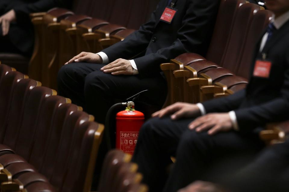 In this Wednesday, March 8, 2017 photo, soldiers in usher uniforms sit and watch near a fire extinguisher during the National People's Congress held at the Great Hall of the People in Beijing. Because safety comes first, fire extinguishers are ubiquitous in and around Beijing’s Great Hall of the People during the annual sessions of China’s ceremonial parliament and its official advisory body. That’s partly for standard purposes of preventing any sort of fire-related emergency that could harm the participants and mar the proceedings. (AP Photo/Andy Wong)