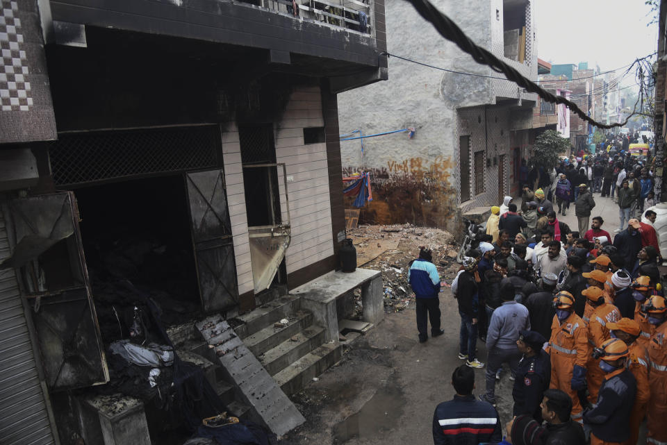 People gather around a warehouse where a fire broke out in the early hours of Monday at Kirari area of New Delhi, India, Monday, Dec.23, 2019. The blaze killed 9 people and left at least 3 injured, a fire official said. (AP Photo)