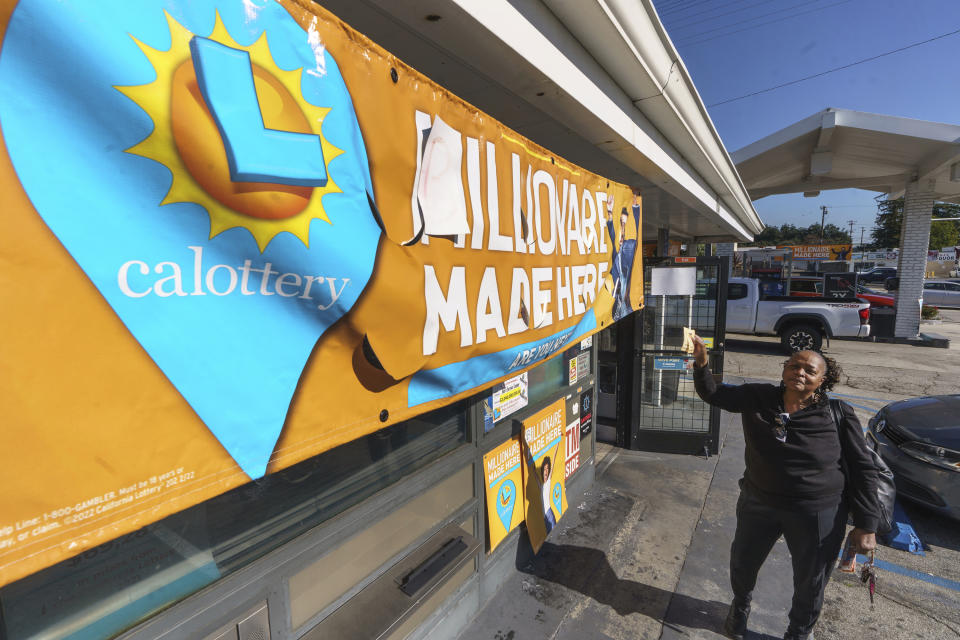 Vivian Knox holds up her newly purchased SuperLotto Plus ticket outside Joe's Service Center, a Mobil gas station that previously sold the $2.04 billion-winning Powerball ticket at Woodbury Road and Fair Oaks Avenue in Altadena, Calif., Friday, Jan. 6, 2023. Lottery players whose numbers didn't hit or who forgot to even buy a ticket will have another shot at a nearly $1 billion Mega Millions prize. The estimated $940 million jackpot up for grabs Friday night has been growing for more than two months and now ranks as the sixth-largest in U.S history. (AP Photo/Damian Dovarganes)