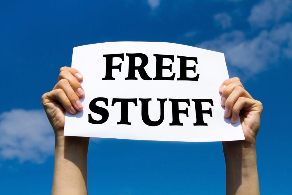 Hands holding a paper sign reading "FREE STUFF" against a blue sky
