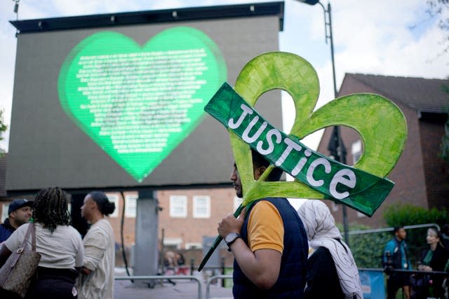 A person holds a heart-shaped sign saying justice