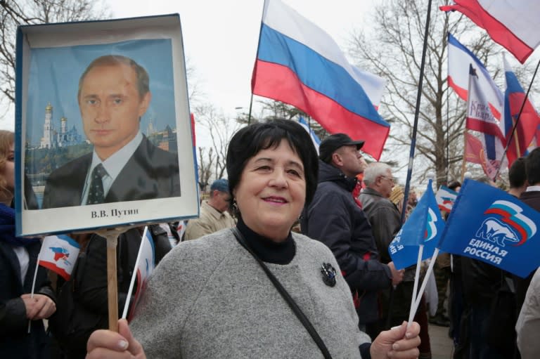 A woman holds a portrait of Russian President Vladimir Putin as she takes part in a rally in Simferopol, on March 16, 2017