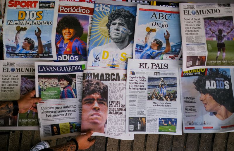 A worker arranges the front pages of Spanish newspapers paying tribute to late soccer legend Diego Maradona at Las Ramblas, in Barcelona