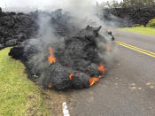 <p>Lava from the Kilauea volcano moves across the road in the Leilani Estates in Pahoa, Hawaii, Saturday, May 5, 2018. Hundreds of anxious residents on the Big Island of Hawaii hunkered down Saturday for what could be weeks or months of upheaval as the dangers from an erupting Kilauea volcano continued to grow. (Photo: Marco Garcia/AP) </p>