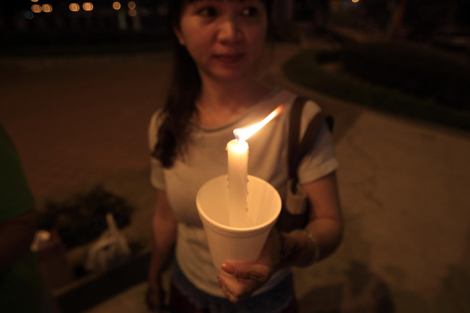 A woman holds a candlelight vigil for passengers aboard a missing Malaysia Airlines plane in Kuala Lumpur, Malaysia, Monday, March 10, 2014. The search operation for the missing Malaysia Airlines Flight MH370 which has involved 34 aircraft and 40 ships from several countries covering a 50-nautical mile radius from the point the plane vanished from radar screens between Malaysia and Vietnam continues after its disappearance since Saturday. (AP Photo/Lai Seng Sin)