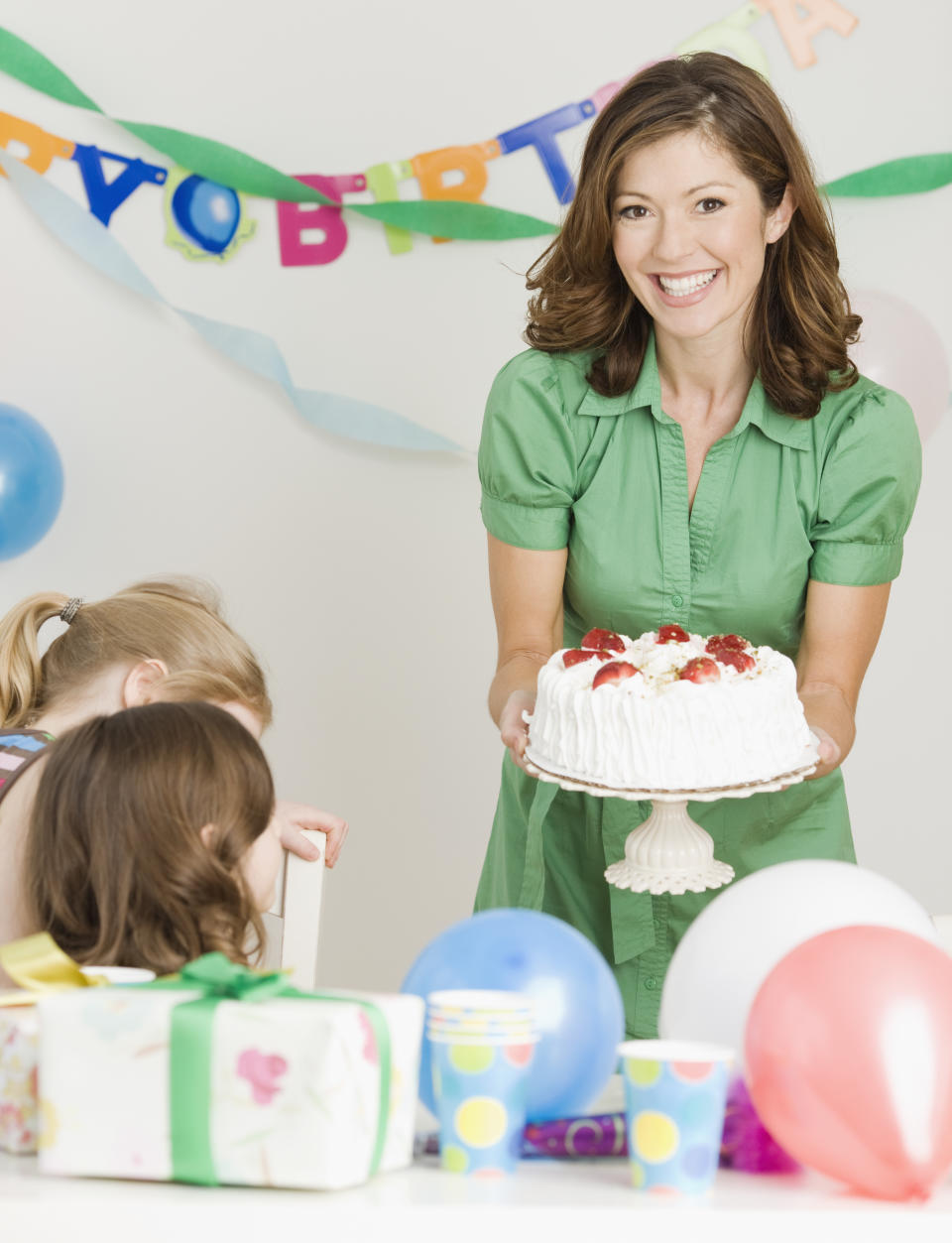 Mother holding birthday cake at party