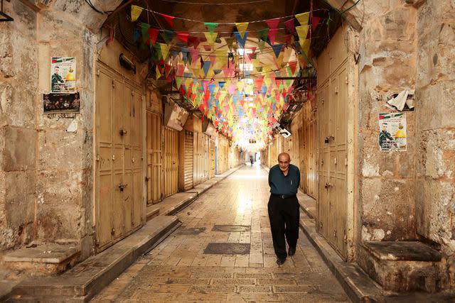 <p>ZAIN JAAFAR/Getty Images</p> A man walks past closed shops in a market area during a general strike in the occupied West Bank city of Nablus on October 8, 2023, following fighting between Israeli forces and the Palestinian militant group Hamas.