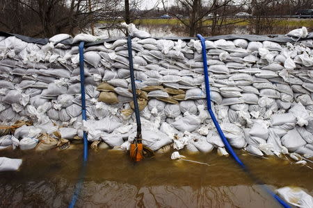 A wall of sandbags and series of pumps are set up to create a barricade to prevent the rising water from flooding a home, following several days of heavy rain, in Arnold, Missouri December 30, 2015. REUTERS/Kate Munsch