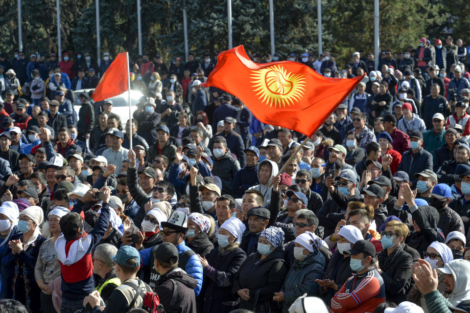Protesters react waving Kyrgyz national flags as they wait for Kyrgyz Prime Minister Sadyr Zhaparov speech in front of the government building in Bishkek, Kyrgyzstan, Wednesday, Oct. 14, 2020. Kyrgyzstan's embattled president has discussed his possible resignation with his newly appointed prime minister in a bid to end the political crisis in the Central Asian country after a disputed parliamentary election. President Sooronbai Jeenbekov held talks with Prime Minister Sadyr Zhaparov a day after refusing to appoint him to the post over concerns whether parliament could legitimately nominate him. (AP Photo/Vladimir Voronin)