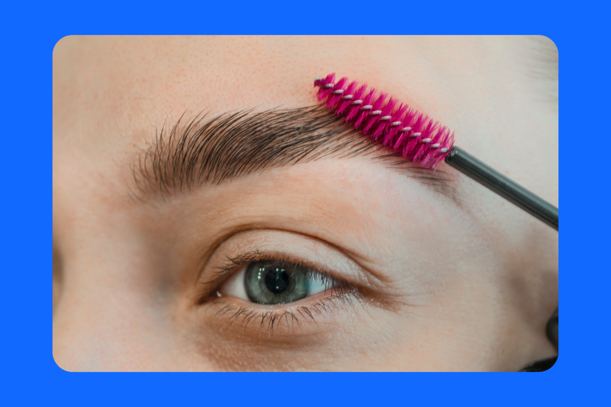 woman brushing brows on colorful background