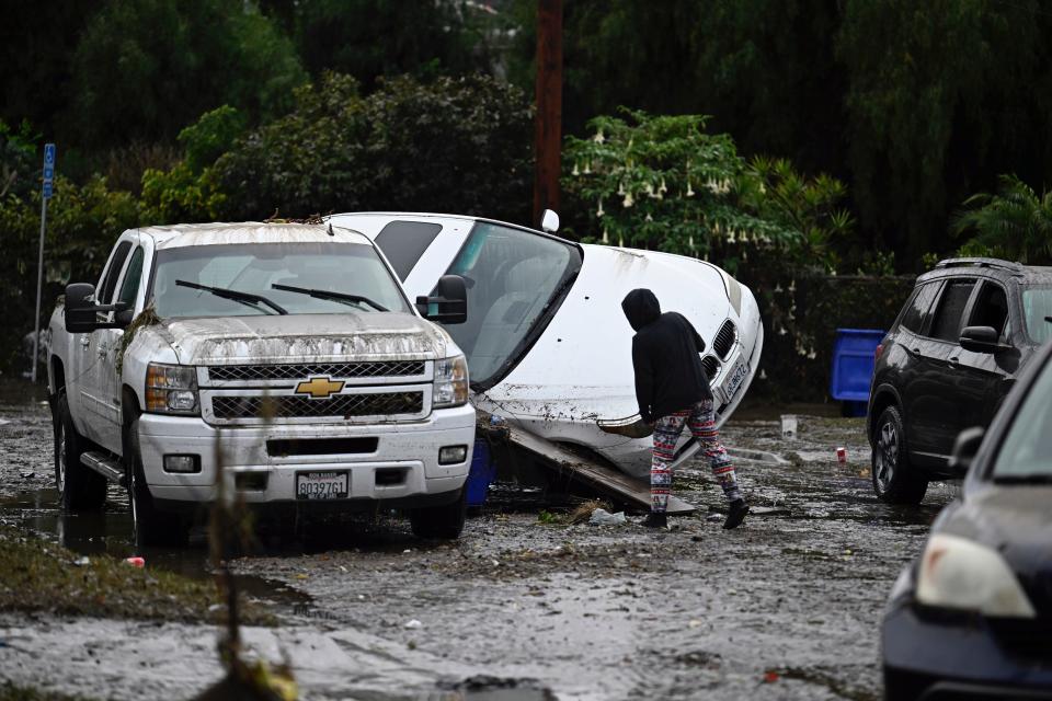 A woman examines cars damaged by floods during a rain storm Monday in San Diego.