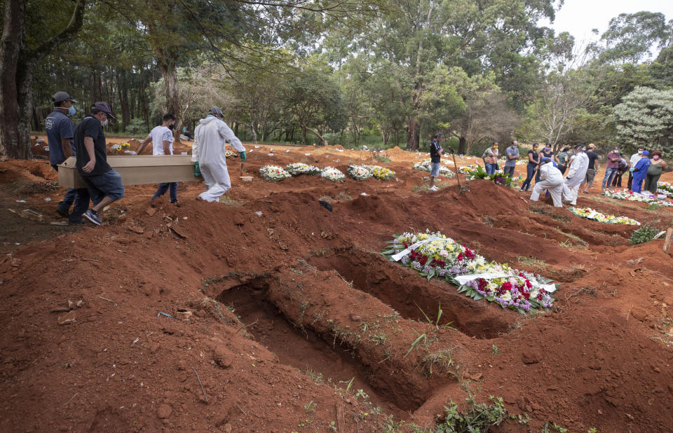 Cemetery workers in protective clothing carry the coffin containing the remains of a person suspected to have died of COVID-19 disease, at the Vila Formosa cemetery in Sao Paulo, Brazil, Thursday, April 30, 2020. (AP Photo/Andre Penner)