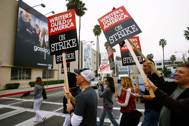 Writers walk up a picket line near a billboard for the television show 