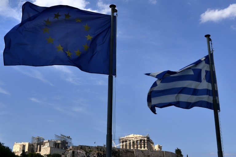 European Union and Greek flags flutter in front of the Acropolis in central Athens on June 26, 2015