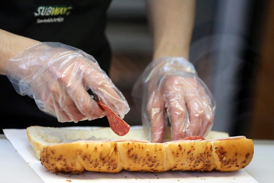 An employee prepares a customer's sandwich order at a Subway fast food restaurant