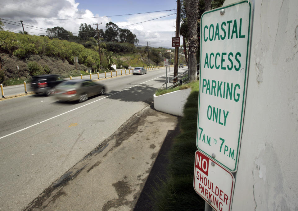 FILE - In this April 20, 2007 file photo a sign directing visitors to two parking spaces next at a coastal access gate for Escondido Beach is shown on Pacific Coast Highway in Malibu, Calif. A new smartphone app that shows users a map of more than 1,500 access points along the California coast was created with help from a tech billionaire whose elaborate wedding ran afoul of state regulators. (AP Photo/Reed Saxon, File)