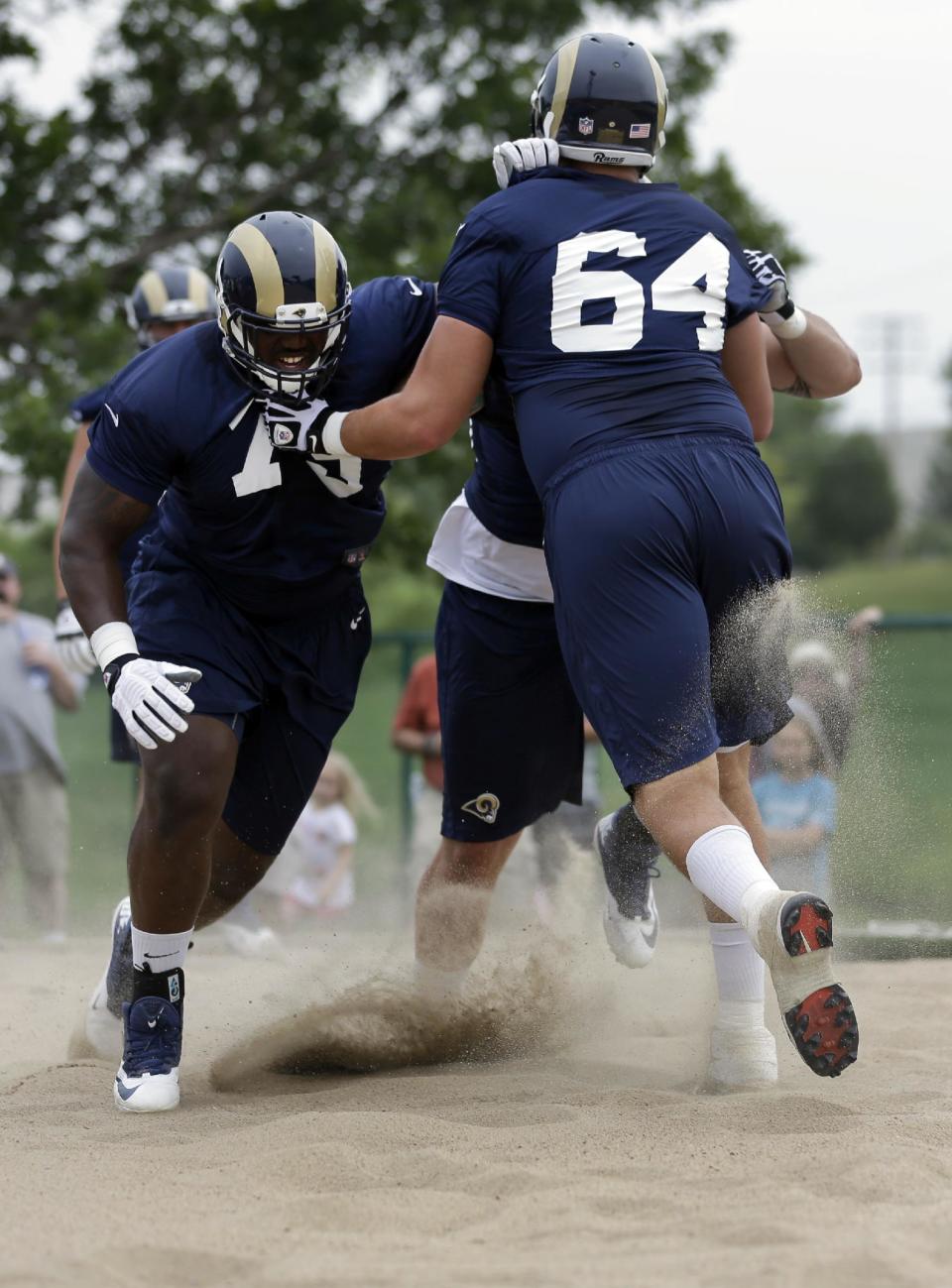 St. Louis Rams' Greg Robinson, left, pushes tackle Sean Hooey (64) in a sand pit during training camp at the NFL football team's practice facility on Saturday, July 26, 2014, in St. Louis. (AP Photo/Jeff Roberson)