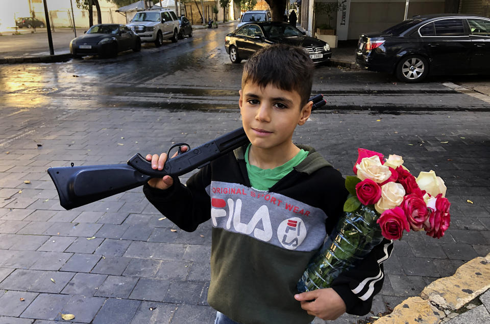 A displaced Syrian boy, Omar, 10, who sells flowers on the street and who fled the war from his hometown of Hassakeh, holds a toy gun and flowers in Hamra street, Beirut, Lebanon, Jan. 31, 2021. UNICEF said Wednesday, March 10, 2021 that Syria’s 10-year-long civil war has killed or wounded about 12,000 children and left millions out of school in what could have repercussions for years to come in the country. The country's bitter conflict has killed nearly half a million people, wounded more than a million and displaced half the country’s population, including more than 5 million as refugees. (AP Photo/Hussein Malla)