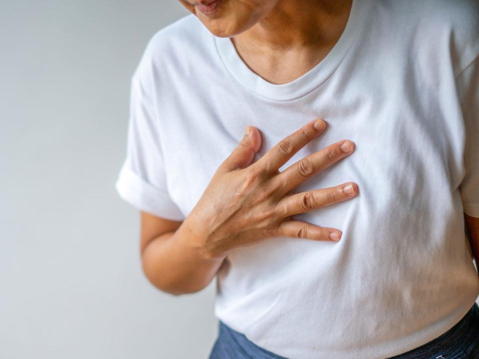 a person holding their chest as if in pain from hearburn