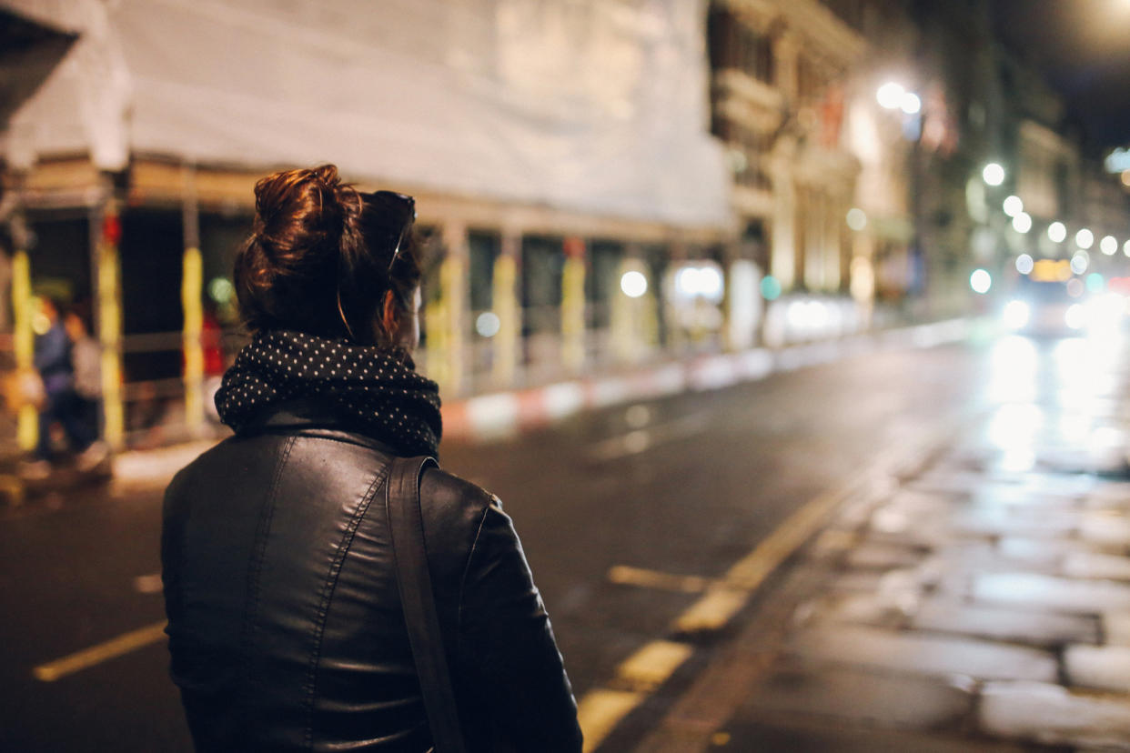 Woman walking down dark street at night. Safe spaces for women needed