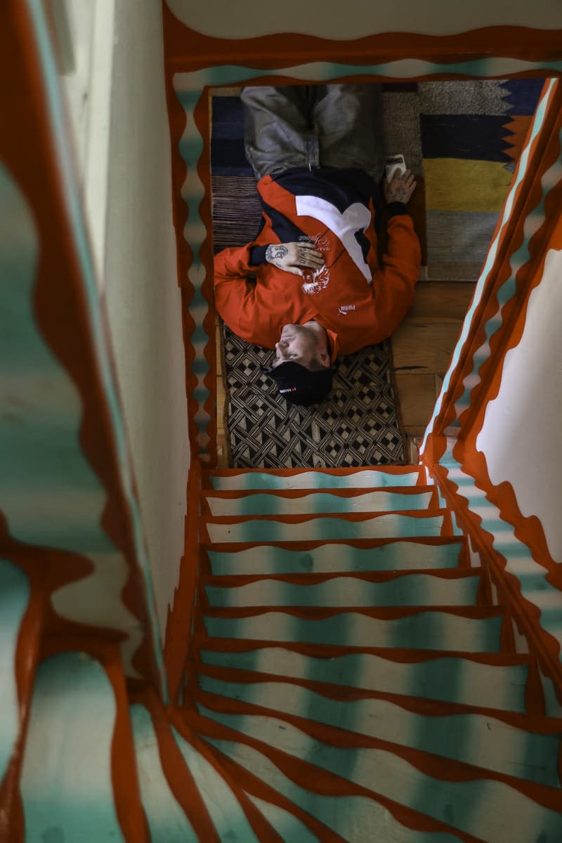 person lying on floor at the bottom of colorful stairs