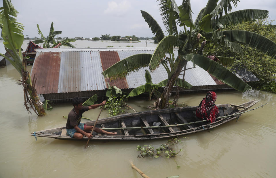 An Indian flood affected man and a woman ride on a country boat in Gagolmari village, Morigaon district, Assam, India, Tuesday, July 14, 2020. Hundreds of thousands of people have been affected by floodwaters and landslides following incessant rainfall in the region. (AP Photo/Anupam Nath)