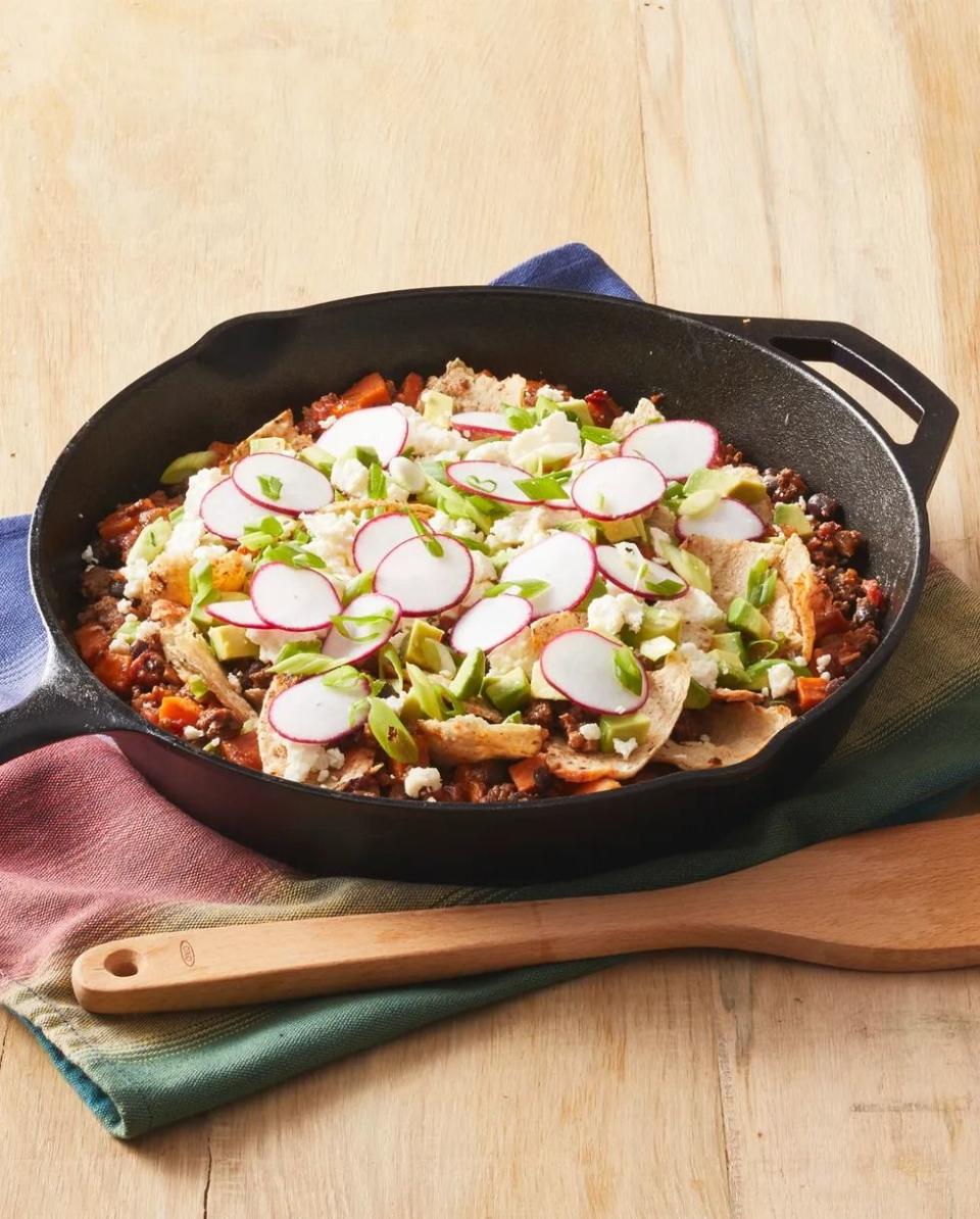 beef taco skillet in cast iron pan with radishes and wooden spoon