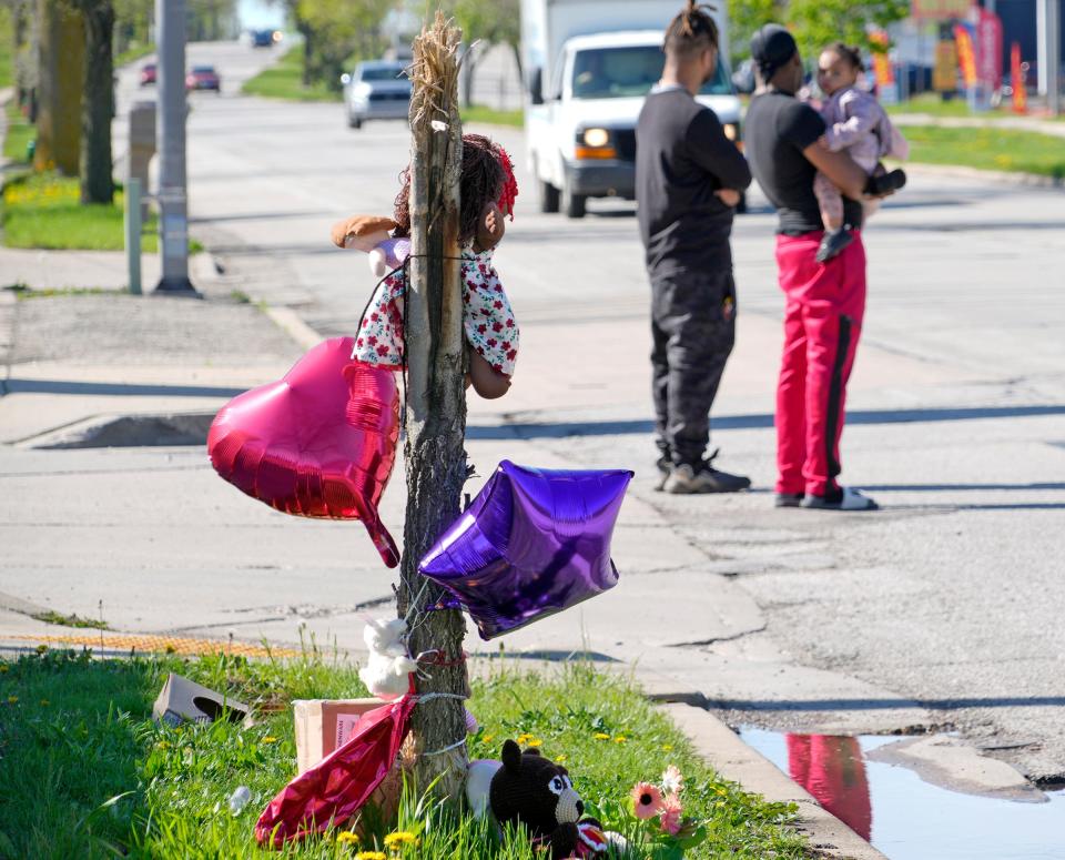 Pedestrians wait for traffic to cross the street as a makeshift memorial is on the scene of hit-and-run that happened on Tuesday that killed a 4-year-old girl and injured her mother at the intersection of North Teutonia Avenue and West Vera Avenue in Milwaukee on Wednesday, May 1, 2024.