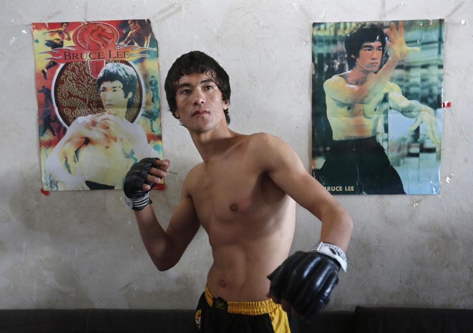 Abbas Alizada, who calls himself the Afghan Bruce Lee, poses for a picture in front of Bruce Lee posters after exercising in Kabul December 9, 2014. From the ruins of an iconic bombed-out palace above Kabul, the young Afghan man bearing a striking resemblance to kung fu legend Bruce Lee is high-kicking his way to Internet fame, aiming to show another side to his war-weary nation. REUTERS/Mohammad Ismail (AFGHANISTAN - Tags: ENTERTAINMENT SOCIETY)