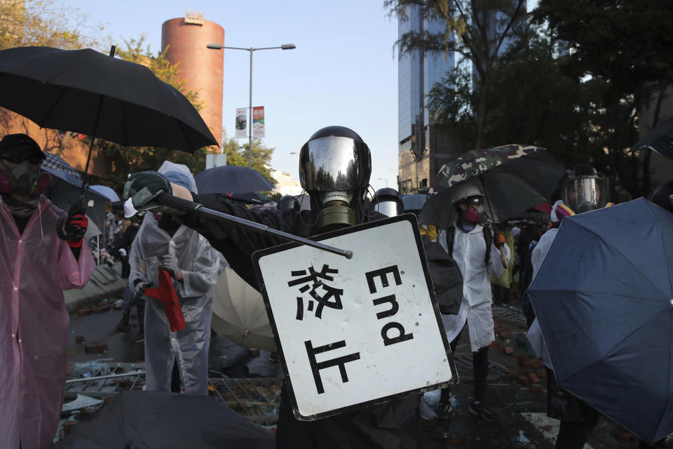 A protestor bangs a metal rod on a street sign during a confrontation at the Hong Kong Polytechnic University in Hong Kong, Nov. 17, 2019. (Photo: Kin Cheung/AP)