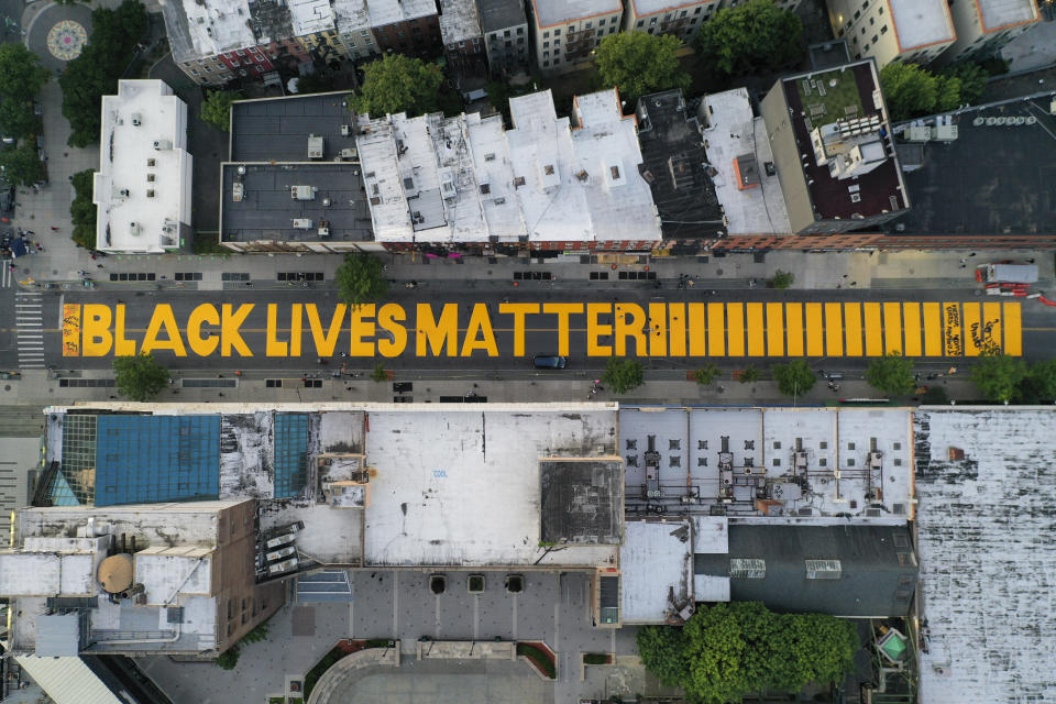 A giant "BLACK LIVES MATTER" sign is painted in orange on Fulton Street, Monday, June 15, 2020, in the Brooklyn borough of New York. (AP Photo/John Minchillo)