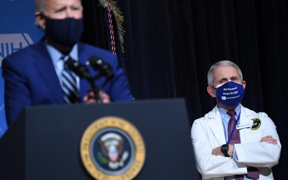 President Joe Biden speaks, flanked by White House Chief Medical Adviser on Covid-19 Dr. Anthony Fauci (R), during a visit to the National Institutes of Health - AFP