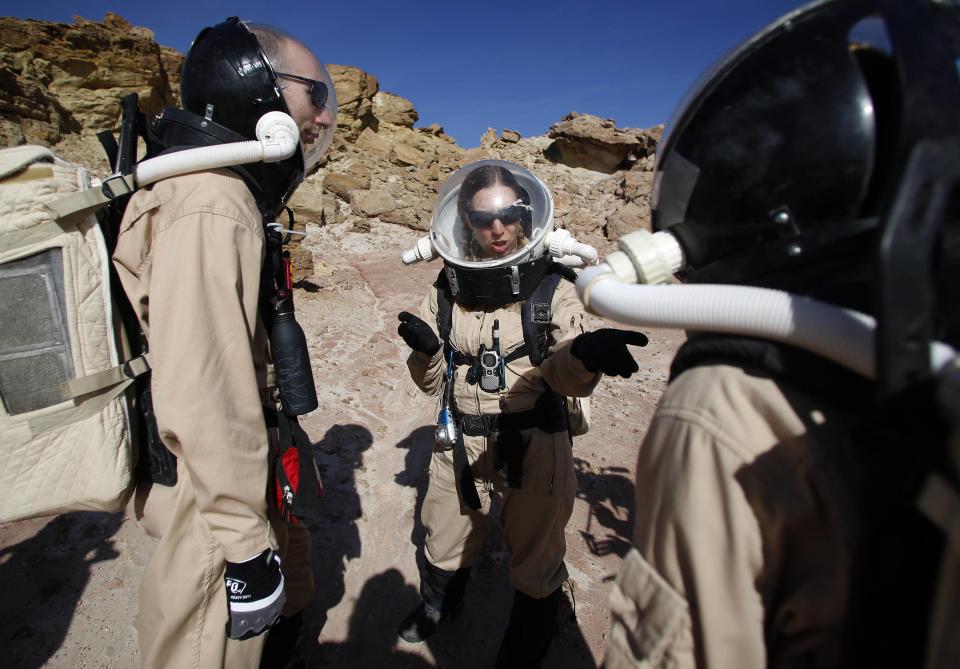 Melissa Battler (C), a geologist and commander of Crew 125 EuroMoonMars B mission, talks to members of the crew about collecting geologic samples for study at the Mars Desert Research Station (MDRS) in the Utah desert March 2, 2013. The MDRS aims to investigate the feasibility of a human exploration of Mars and uses the Utah desert's Mars-like terrain to simulate working conditions on the red planet. Scientists, students and enthusiasts work together developing field tactics and studying the terrain. All outdoor exploration is done wearing simulated spacesuits and carrying air supply packs and crews live together in a small communication base with limited amounts of electricity, food, oxygen and water. Everything needed to survive must be produced, fixed and replaced on site. Picture taken March 2, 2013. REUTERS/Jim Urquhart