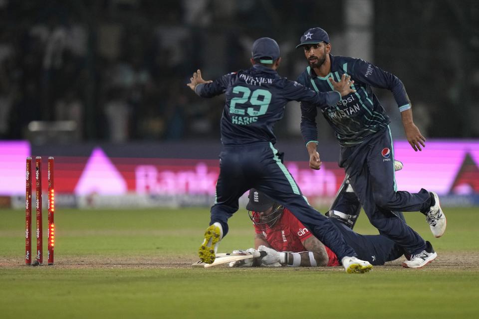Pakistan's Shan Masood, right, and Mohammad Haris, left, celebrate after England's Reece Topley, center, run out during the fourth twenty20 cricket match between Pakistan and England, in Karachi, Pakistan, Sunday, Sept. 25, 2022. (AP Photo/Anjum Naveed)